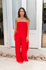 Conjunto de dos piezas color beige claro, compuesto por un top strapless con bajo asimétrico y un pantalón ancho de tiro alto.