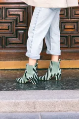 Botines de cuero con estampado de cebra en tonos verde claro y negro, con puntera fina y tacón cuadrado. Presentan paneles laterales elásticos en color verde liso.