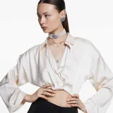 Colgante con cadena plateada y dije en forma de concha de mar con cristal central azul y circonitas blancas.