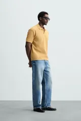 Polo azul marino de punto con textura acanalada vertical, corte regular fit, cuello solapa con abertura frontal y mangas cortas.