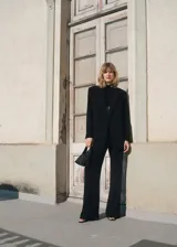 Blazer negro de corte recto, con cuello de pico cruzado y cierre de un solo botón. Presenta solapas con muesca, bolsillo de ribete en el pecho y dos bolsillos de solapa laterales.