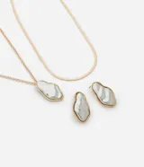 Conjunto de collar de doble cadena dorada y aros con colgantes orgánicos con borde dorado y centro marmolado en tonos grises.