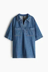 Vestido corto de denim azul, con cuello camisero, escote en V, manga corta y dos bolsillos de parche en el pecho.