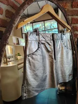 Minifalda plateada de cuero con corte asimétrico, bolsillos delanteros y detalles de remaches metálicos.