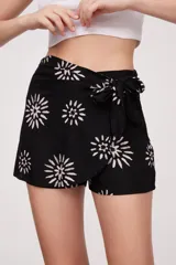 Short negro con estampado de flores blancas, corte evasé y lazo en la cintura.