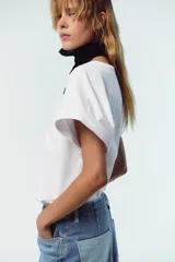 Camiseta blanca de algodón con cuello redondo, manga corta y bolsillo de plastrón en el delantero.