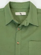 Camisa azul de manga corta confeccionada en algodón ligero con textura waffle. Presenta corte cuadrado, bolsillo en el pecho y botones de coco grabados con el logo de Polonio.