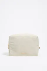 Neceser grande Bimba y Lola color beige, de nylon con estructura blanda y cierre de cremallera. Tiene un bolsillo interior, tirador de piel y logo metálico.