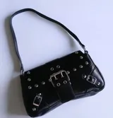 Cartera negra con correa corta para el hombro, con apliques de tachas y hebillas plateadas.