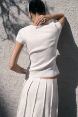 Remera corta de punto fino color blanco, entallada y con cuello redondo ribeteado acanalado.