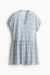 Vestido túnica corto blanco con estampado floral azul, cuello mao y abertura en V. Mangas cortas con doblez, botones forrados y costura fruncida en la cadera. Corte holgado.