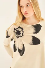 Sweater color crema con estampado de flor en tonos grises y negros en el frente.
