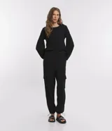 Pantalón negro de suedine con cintura elástica, bolsillos laterales con solapa y ajuste con tirador en el tobillo.