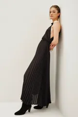 Vestido largo negro con escote halter, falda plisada y cintura elástica.