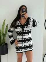 Vestido corto tejido a crochet, con escote en V y mangas largas acampanadas. Diseño a rayas horizontales en blanco y negro.