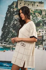 Vestido corto negro con patrón calado cuadrado, cuello redondo y mangas cortas con terminaciones a contratono en blanco.