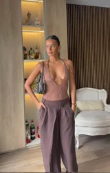 Body de encaje negro con escote en V profundo, tirantes halter con detalles metálicos y corte tipo tanga.