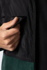 Campera negra con la parte superior de tela tipo rompevientos con dos bolsillos con solapa y la parte inferior de micro polar. Tiene cierre frontal y cuello alto.