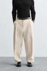 Pantalón negro de corte amplio, tipo balloon fit, con pinzas en la cintura, bolsillos laterales y traseros de ojal.