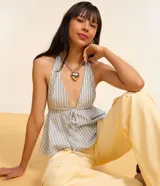 Blusa peplum con escote halter y lazo en el frente, con patrón de rayas verticales azules y blancas.