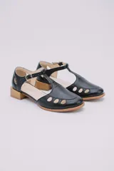 Sandalias bajas negras de cuero con pulsera al tobillo y talón cubierto. Presentan aberturas circulares en la capellada y taco de madera.