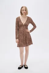 Vestido corto color beige con estampado animal print, escote en V, mangas largas y falda evasé con volados. Ajuste con lazo en la cintura.