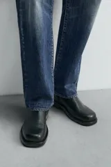 Bota de cuero negra con cierre de cremallera lateral, plantilla de cuero, horma cuadrada y tacón bajo.