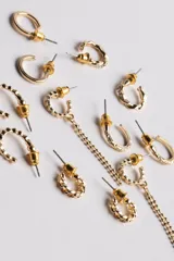 Pack de seis pares de aros dorados con diferentes diseños: aros tipo argolla con textura, aros con dije de estrella, aros con cadena colgante y aros lisos.