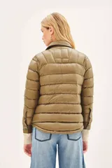 Campera puffer color beige con cuello camisero, cierre con botones a presión, bolsillos con solapa en el pecho y relleno de plumas.