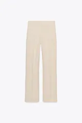 Pantalón de vestir color beige, de tiro alto, con cintura elástica en la parte trasera, bolsillos delanteros y falsos bolsillos de vivo en la parte trasera.