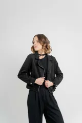 Chaqueta color beige de tela tipo gamuza con elastano, cuello solapa, manga larga con trabillas en hombro, bolsillos delanteros con cremallera metálica y cierre frontal con cremallera.