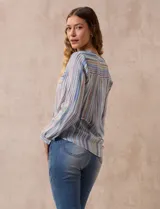 Blusa de gasa estampada a rayas verticales en tonos celeste, lila, naranja y marrón. Tiene cuello a la base con escote en V y botones. Delantera con bolsillo aplicado. Largo de manga regulable con presilla y botón. Terminación anudada opcional.