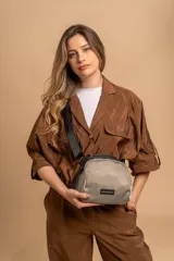 Bandolera pequeña de tela negra, con correa ancha ajustable y cierre superior.