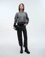Buzo gris de lana con cuello redondo, manga ranglán, pinzas en los hombros y cierre metálico en una sisa delantera.