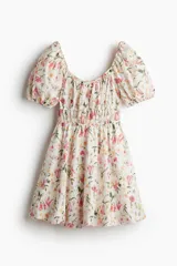 Vestido corto de algodón con estampado floral, escote cuadrado con volados, mangas cortas abullonadas con elástico y cintura elastizada.