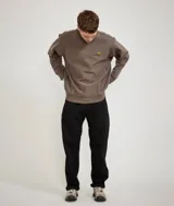 Buzo de cuello redondo, color negro, con el logo de Carhartt bordado en el pecho en tonos naranja y amarillo.