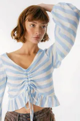 Blusa blanca de lino con escote en V, mangas largas abullonadas y frunce central.