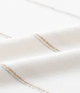 Remera de viscolycra color crema con rayas horizontales doradas, cuello redondo y mangas cortas.