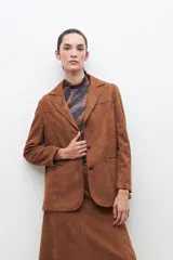 Blazer color tostado de similar gamuza, con diseño clásico de botones y corte entallado.