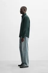 Camisa azul marino de corte regular fit, confeccionada en tejido de algodón Oxford. Tiene cuello abotonado, manga larga con puños abotonados, bolsillo de parche en el pecho y cierre frontal con botones.