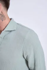 Camisa de manga larga color gris oscuro, con cuello clásico y cierre frontal con botones.