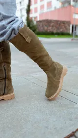 Bota alta de cuero color verde oliva, con caña alta y suela track color beige.