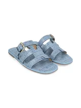 Sandalias chatitas celestes con textura croco, tiras cruzadas y hebilla metálica de ajuste en el empeine.