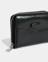 Billetera negra de cuerina con efecto acharolado, solapa con broche y cierre perimetral con cremallera.