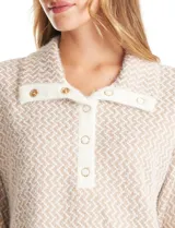 Buzo de tejido estampado en zigzag beige y blanco, con escote amplio, botones a presión en el cuello y mangas largas. Presenta botones a presión decorativos en los laterales.