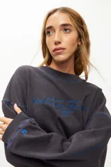 Buzo gris de corte holgado con bordado azul en el frente y costuras a contratono.