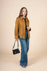 Camisa marrón de corte clásico, con tejido suave y textura cálida. Tiene un bolsillo decorativo discreto y botones al tono.