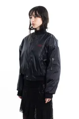 Campera bomber negra de tela satinada con cierre frontal, cuello redondo y puños y cintura elastizados. Tiene un pequeño logo bordado en el pecho y un bolsillo con cierre en la manga. Es reversible.