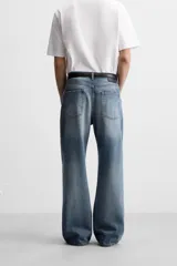 Pantalón de jean celeste con efecto lavado, corte flare fit y caída baggy desde la rodilla hasta el tobillo. Tiene cinco bolsillos y cierre frontal con botones.