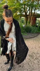 Ruana tejida a mano en color lila, confeccionada en lana merino. Presenta un diseño de punto con calados diagonales y terminación de flecos largos en el ruedo.